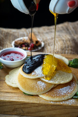 pancakes stacked on a wooden board, drizzled with honey and chocolate, macro photo