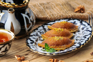 Fried sweet oriental cakes on a plate on a background with tea