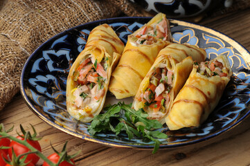 pancakes with filling wrapped in rolls on a beautiful plate on a background