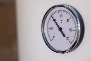 Close-up image of a round thermometer displaying temperature in Celsius, mounted on a white wall, showcasing precision measurement in a clean and minimalistic environment