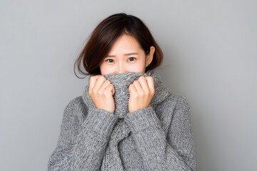 woman burying her face in scarf attempting to hide her tears on clean solid background