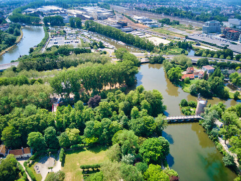 Aerial view of waterways intertwining through verdant trees, creating a serene tapestry alongside the cityscape, Bruges, Flanders, Belgium.