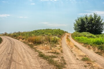 a fork in two country roads that skirt an ancient burial mound on a plain in southern Russia on a hot sunny summer day