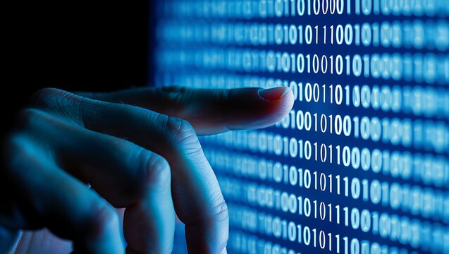 Close up of a hand interacting with a glowing blue screen displaying lines of binary code representing digital data and technology