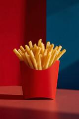 Perfectly crisp golden fries in a red container against a vibrant blue and red backdrop