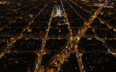 Aerial view of Barcelona's grid-patterned streets glowing with warm light, showcasing the iconic Sagrada Familia standing tall, Barcelona, Spain.