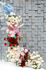 Wedding arch decorated with colorful flowers and chandeliers illuminating the gray stone wall