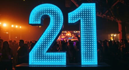 A large illuminated number "21" stands prominently in front of a crowd at a celebration.