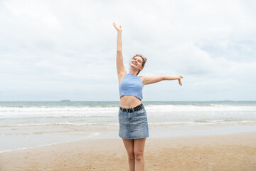 Young woman joyful arms raised on the tropical beach. Female traveling on vacation in summer