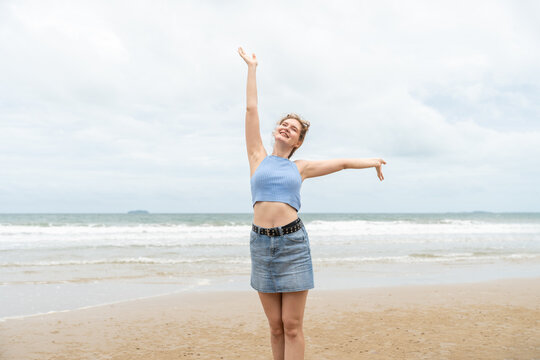 Young woman joyful arms raised on the tropical beach. Female traveling on vacation in summer - Powered by Adobe