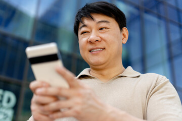 Asian businessman smiling and using smartphone for online shopping