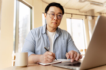 Asian Freelancer Working From Home Office Taking Notes on Notebook