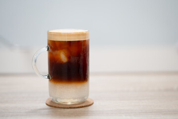 Glass of iced coffee in coffee on wooden table.