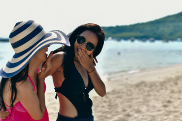 Two friends enjoying a sunny day at the beach, sharing laughter and smiles while dressed in vibrant beachwear.