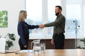 Business partners shaking hands in office, selective focus