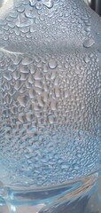 A small condensation droplets forming on a smooth surface. The soft blue tones and perfect curvature of water droplets evoke a fresh, calm. Wellness, hydration or skincare  concept.
