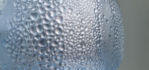 A close-up of condensation droplets forming on a smooth surface. The soft blue tones and perfect curvature of water droplets evoke a fresh, calm, and pure atmosphere — a quiet tribute to the beauty of