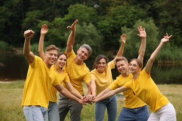 Team building. Group of happy people joining hands outdoors