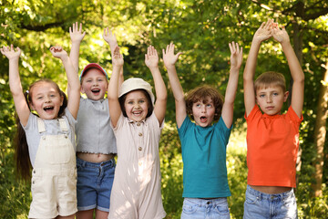 Happy children with raised hands in nature