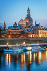 Fototapeta premium Panoramic view of Dresden old town from the Elbe riverbank, with baroque churches, domes, and historic buildings under clear sky. Famous cultural landmark in Saxony, Germany