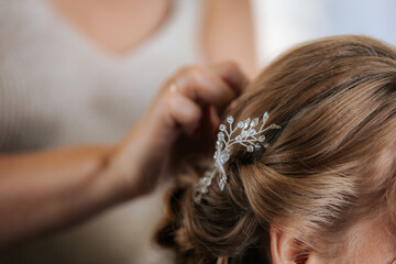Naklejka premium Close-up of a bride with closed eyes as a makeup artist applies eye shadow with a brush, capturing a serene and intimate bridal prep moment.
