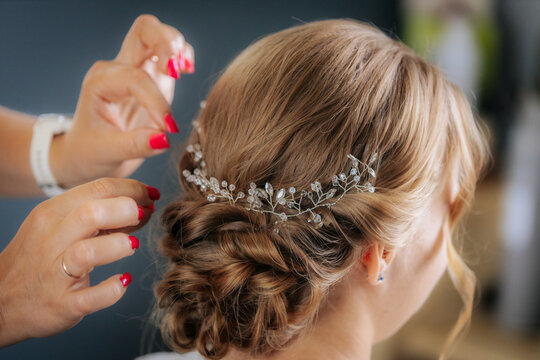 Close-up of a bride with closed eyes as a makeup artist applies eye shadow with a brush, capturing a serene and intimate bridal prep moment.