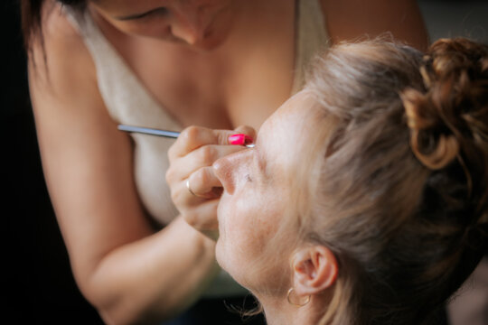 Close-up of a woman receiving professional makeup, with a focus on eye makeup being carefully applied by a makeup artist.