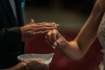 A close-up moment of a bride gently placing a gold wedding ring on the groom’s finger during their marriage ceremony. Intimate and symbolic gesture.