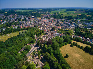 Aerial view of the quaint town nestled amidst vibrant green forests and golden fields, a tapestry of natural beauty and human settlement, Valkenburg, Limburg, Netherlands.
