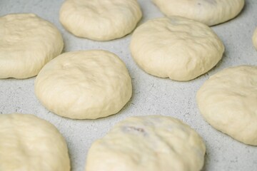 Freshly prepared dough rounds resting on a smooth surface, showcasing the texture and softness of...