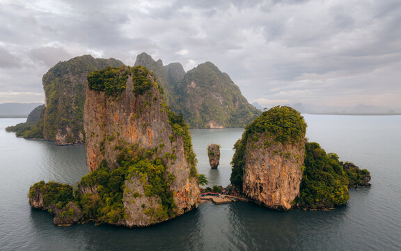 Aerial view of James Bond Island's iconic limestone karsts rise majestically from the emerald waters under a brooding sky, Phang Nga Bay, Thailand.