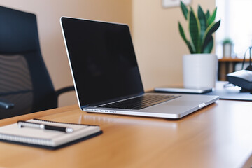 A neat and organized desk setup with a laptop, notepad, and pen in a modern office