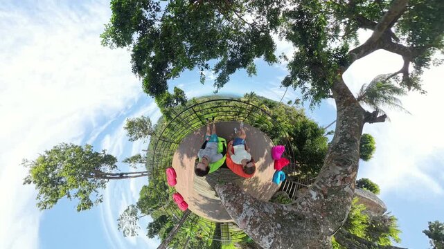 Man and Woman Sitting on Colorful Bean Bags with Tree Branch Arching Overhead in Tiny Planet View, Tiny Planet Effect, Shared Escape Concept
