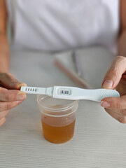 Female hand holding positive pregnancy test strips and urine test. False positive pregnancy test...