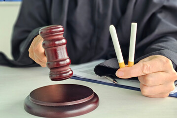 Judge holding gavel and cigarettes in courtroom during legal proceedings concept