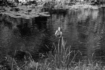 Portrait of a young beautiful girl near a forest river. Black and white photo.