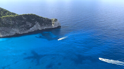 Vibrant blue waters and rocky coastline with boats cruising in a serene landscape