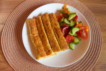 Fried pancakes are stuffed and rolled up served on dish