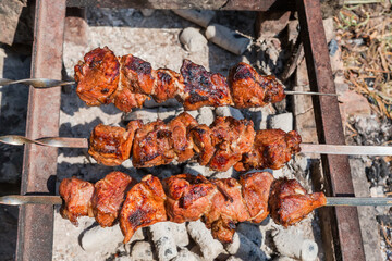 Shashlik on metal skewers during of grilling on mangal outdoors