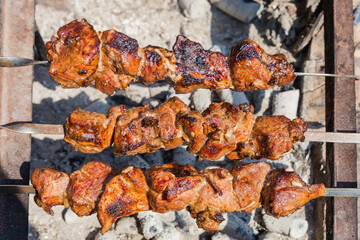 Shashlik on metal skewers during of grilling outdoors, top view
