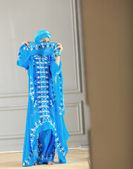 Young east woman in oriental clothes of blue color. Woman covers her face.