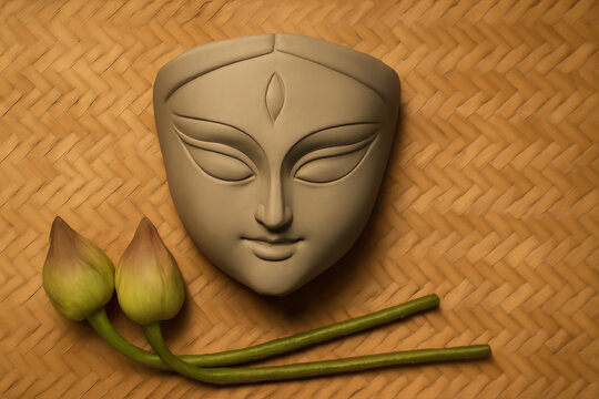 A clay face of Devi Durga with a small flower on each side