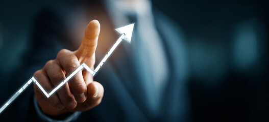 Businessman touching a glowing upward arrow graph symbolizing business growth, success, and financial progress


