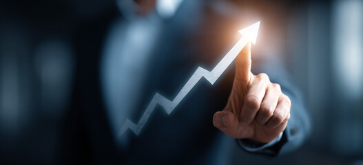 Businessman touching a glowing upward arrow graph symbolizing business growth, success, and financial progress

