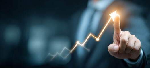 Businessman touching a glowing upward arrow graph symbolizing business growth, success, and financial progress

