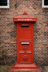 Obraz premium traditional old Dutch red postbox mounted in a cotswold stone wall