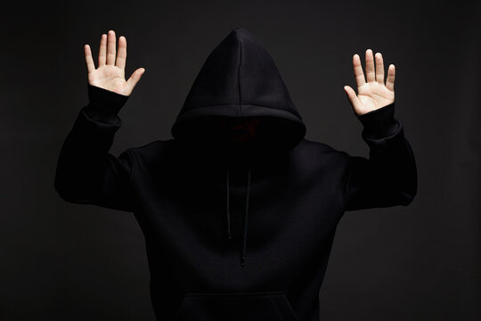 hooded man surrenders raising his hands up to be arrested