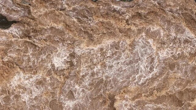 High-pressure flood water in mountain river tributary. A mountain river or stream raging in a flash flood. Upstream view over the turbulent waters.