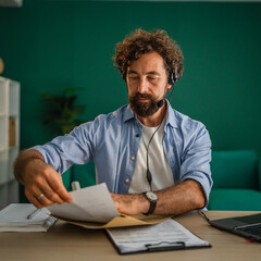 Focused entrepreneur managing documents during a video conference call from home office