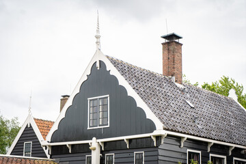 Dutch typical landscape. Traditional old dutch windmill with old houses against blue cloudy sky in the Zaanse Schans village, Netherlands. Famous tourism place. Sheep grazing on green grass.